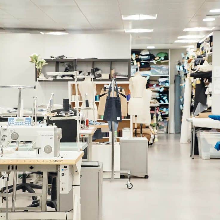 Modern sewing workspace with industrial sewing machines, mannequins, and fabric storage. Ideal for fashion design and garment production.