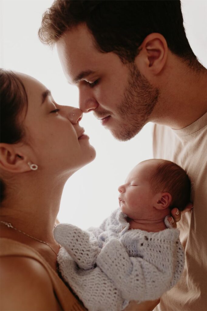 Sessão de Fotos Newborn em Estúdio - Estúdio Pitori Loving parents embracing their newborn baby, wrapped in a knit blanket, showcasing a tender family moment. | Sky Rye Design Loving parents embracing their newborn baby, wrapped in a knit blanket, showcasing a tender family moment.