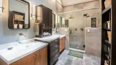 Modern bathroom with double sinks, glass shower, and elegant wood cabinetry. Bright and spacious design with contemporary fixtures.