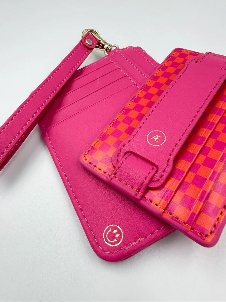 Pink leather cardholder with a checkered pattern, featuring multiple slots and a detachable strap on a white background.