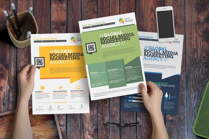 Three social media marketing agency flyers being held over a wooden desk with a smartphone, glasses, and pencils nearby.