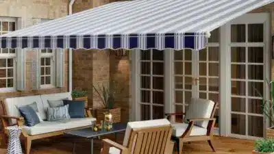 Outdoor patio with striped awning, comfortable seating, and wooden furniture, creating a cozy space for relaxation and gatherings.