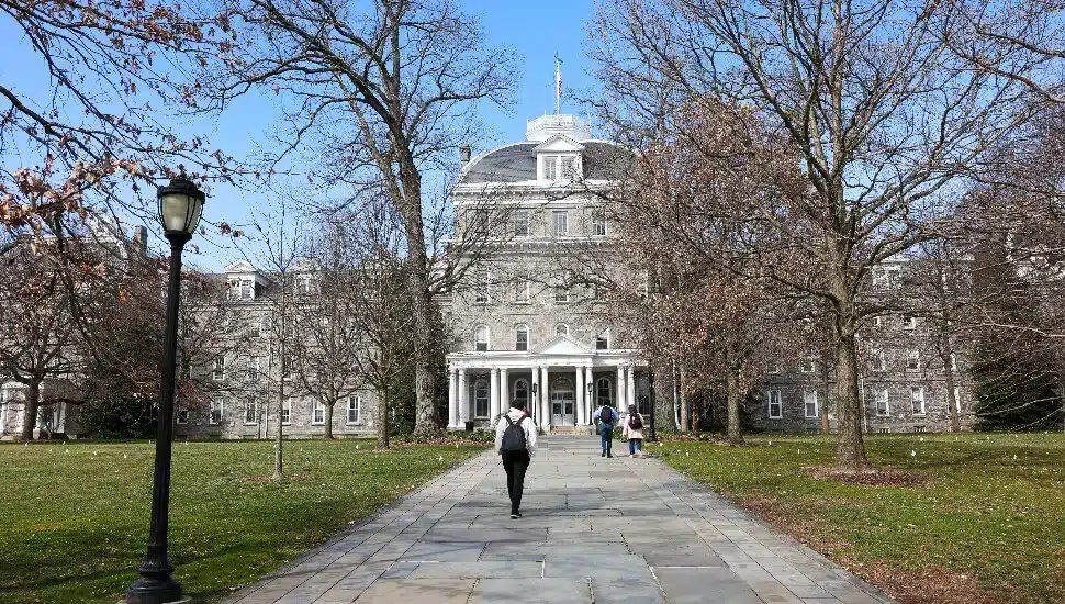 Swarthmore-College-1jpg Historic, stone university building with students walking on a path, amidst trees and a garden, under a clear blue sky. | Sky Rye Design Historic, stone university building with students walking on a path, amidst trees and a garden, under a clear blue sky.