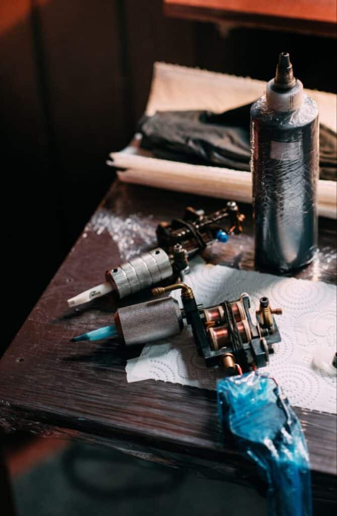 Tattoo machine and ink bottle on a wooden table in a tattoo studio, ready for use.
