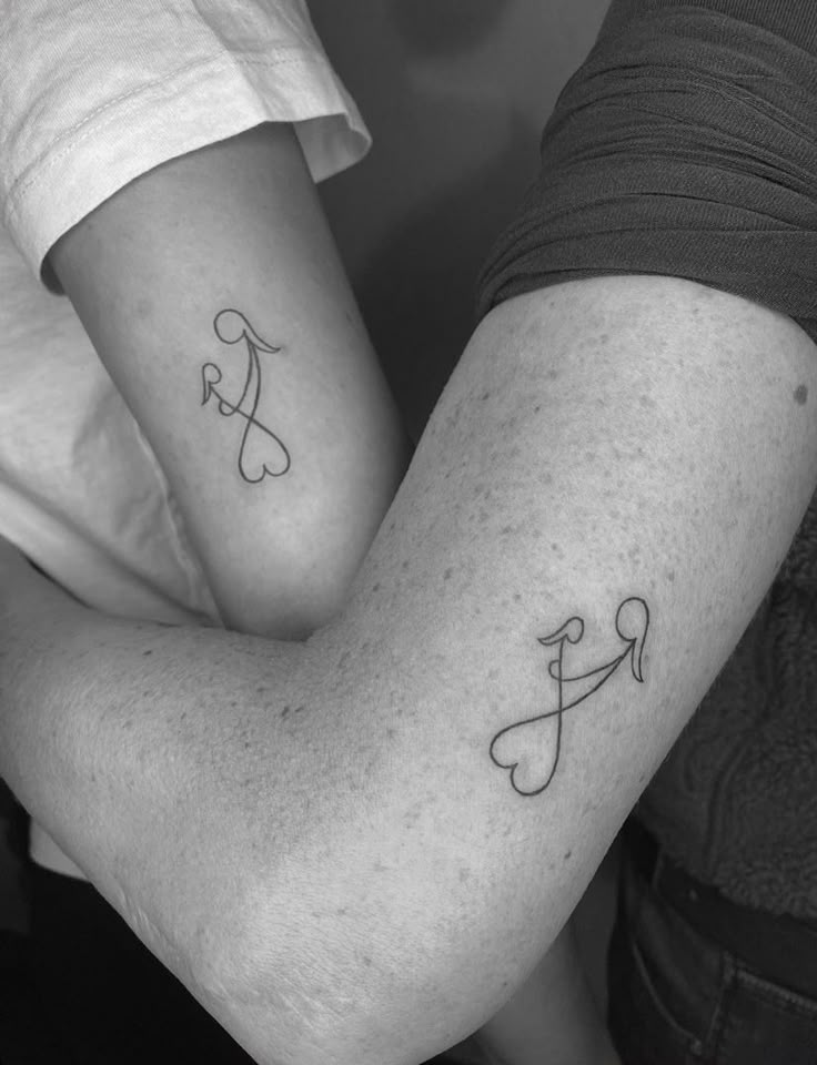 Tattoo mum and daughter Two arms with matching minimalist tattoos featuring arrows and hearts, symbolizing connection and love. Black and white image. | Sky Rye Design Two arms with matching minimalist tattoos featuring arrows and hearts, symbolizing connection and love. Black and white image.
