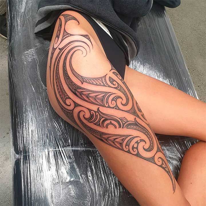 Thigh Tattoo Intricate tribal tattoo design covering a woman's thigh, showcasing detailed curves and patterns with artistic black ink. | Sky Rye Design Intricate tribal tattoo design covering a woman's thigh, showcasing detailed curves and patterns with artistic black ink.