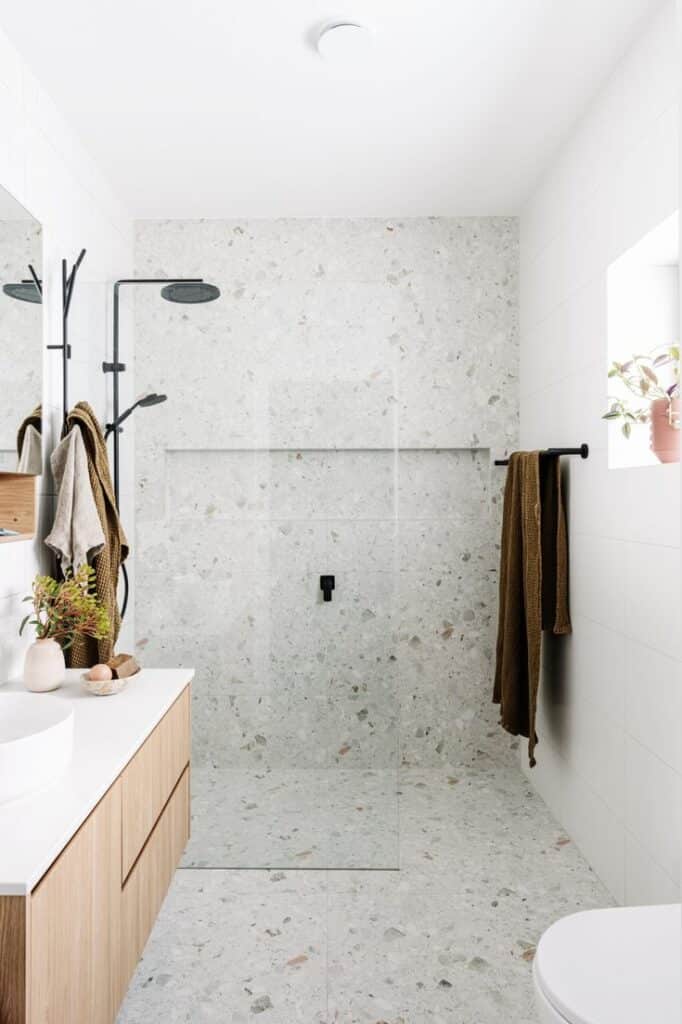 This Melbourne passive house proves sustainability is stylish Modern bathroom with glass shower, terrazzo tiles, wooden vanity, and minimalist decor. Bright natural light streaming in. | Sky Rye Design Modern bathroom with glass shower, terrazzo tiles, wooden vanity, and minimalist decor. Bright natural light streaming in.