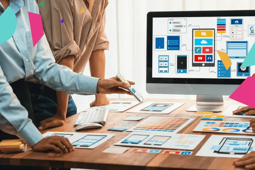 Team working on mobile app design with wireframes displayed on computer, using digital tools for collaborative interface development.