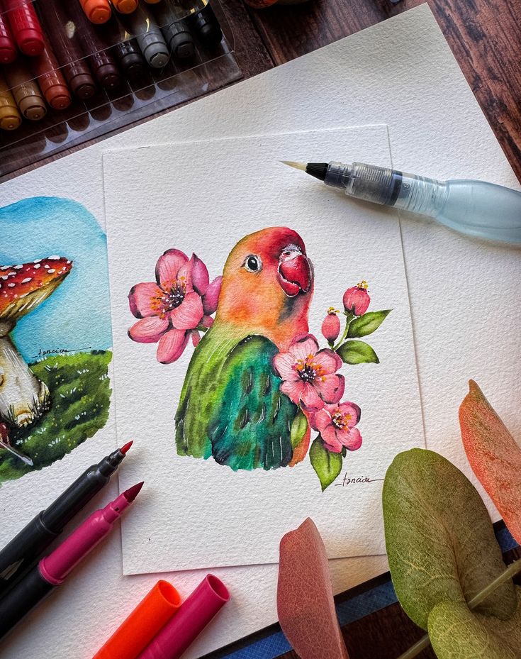 Colorful parrot watercolor painting with pink blossoms, surrounded by art supplies on a wooden table. Perfect for nature and art enthusiasts.