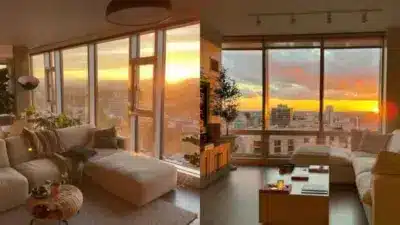 Modern living room with cozy seating, large windows, and stunning cityscape at sunset creating a warm, inviting ambiance.
