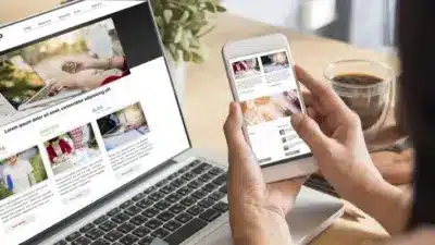 Person browsing an online shop on a smartphone and laptop, with a cup of coffee nearby, highlighting responsive web design.