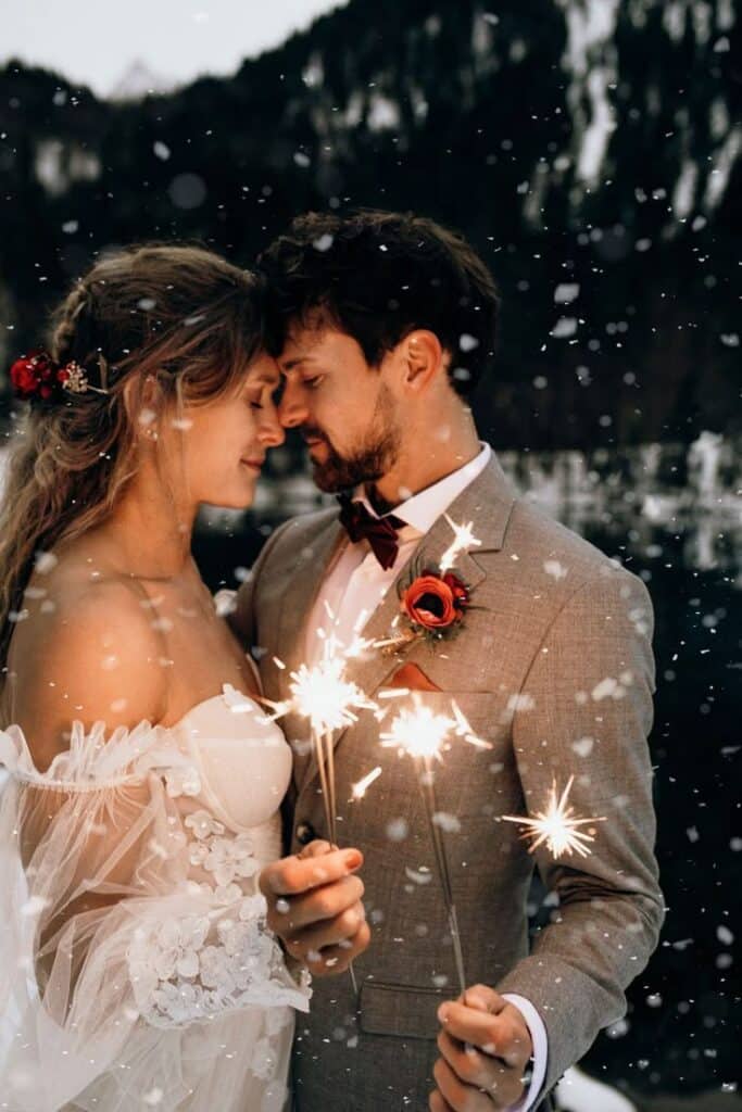Winterlich Heiraten im Kleinwalsertal - Hochzeitswahn Romantic couple embraces with sparklers in a snowy, mountain landscape, capturing a magical wedding moment. | Sky Rye Design Romantic couple embraces with sparklers in a snowy, mountain landscape, capturing a magical wedding moment.