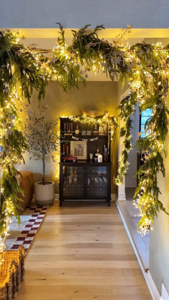 a6e64454f1d2cb2bd6ac96871d3a62d3 Festive living room archway adorned with evergreen garlands and twinkling lights, leading to a beautifully decorated cabinet. | Sky Rye Design Festive living room archway adorned with evergreen garlands and twinkling lights, leading to a beautifully decorated cabinet.