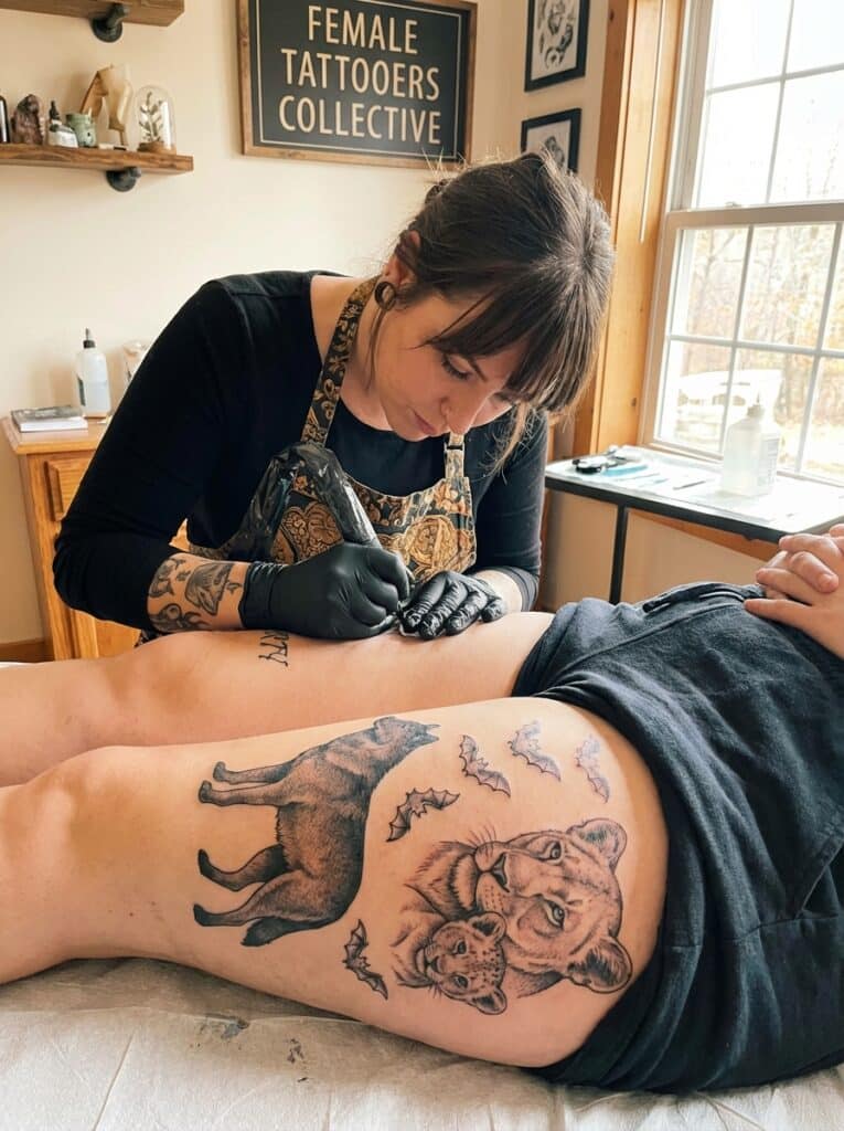 ai-photo-studio-1765824065341-1 Tattoo artist inking wildlife design on thigh at Female Tattooers Collective studio. | Sky Rye Design Tattoo artist inking wildlife design on thigh at Female Tattooers Collective studio.