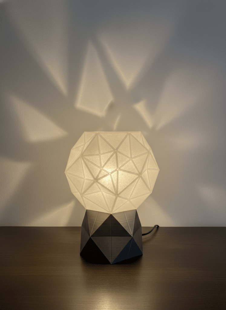 ai-photo-studio-1765921983790-2 Modern geometric table lamp casting intricate shadow patterns on a wall, providing ambient lighting for stylish interior decor. | Sky Rye Design Modern geometric table lamp casting intricate shadow patterns on a wall, providing ambient lighting for stylish interior decor.
