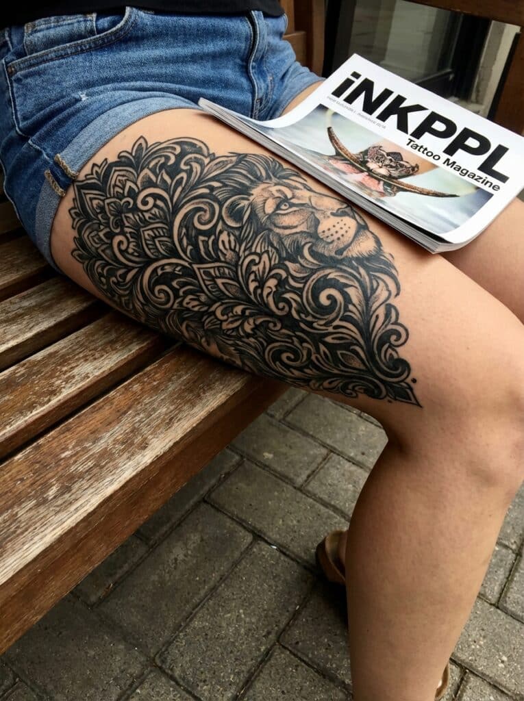 ai-photo-studio-1765998388060-1 Lion thigh tattoo in intricate design with magazine, INKPPL Tattoo Magazine, on wooden bench. | Sky Rye Design Lion thigh tattoo in intricate design with magazine, INKPPL Tattoo Magazine, on wooden bench.