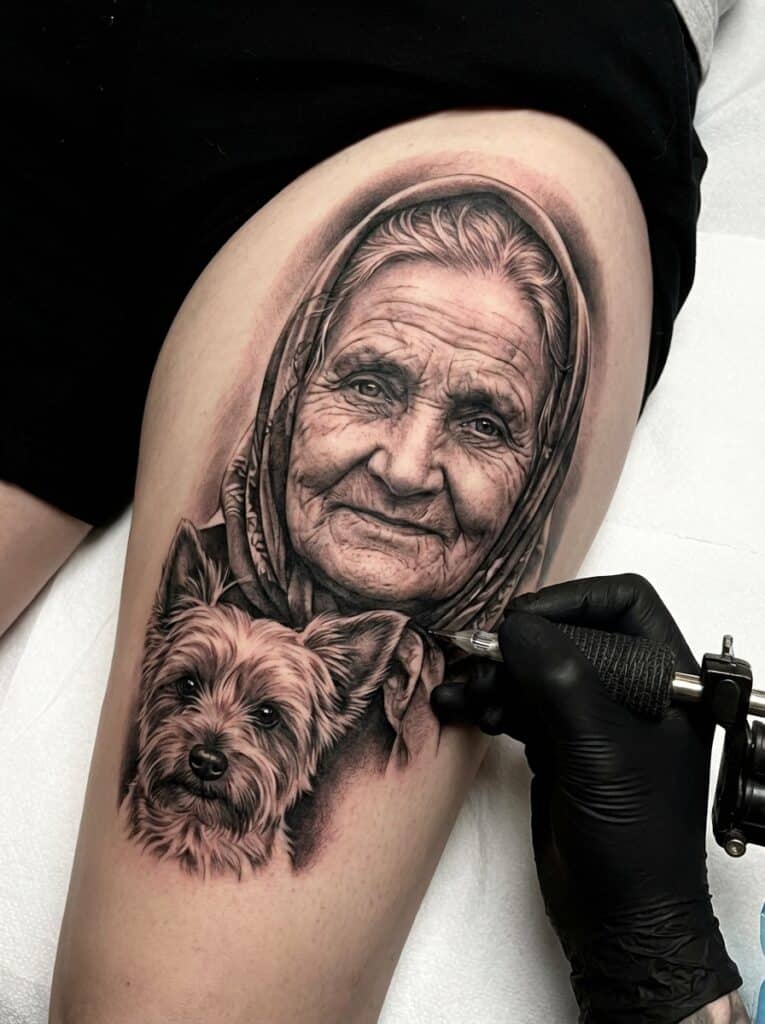 ai-photo-studio-1765998659423-1 Black and gray tattoo of elderly woman and dog on thigh with tattoo artist's hand using machine. Detailed portrait art. | Sky Rye Design Black and gray tattoo of elderly woman and dog on thigh with tattoo artist's hand using machine. Detailed portrait art.