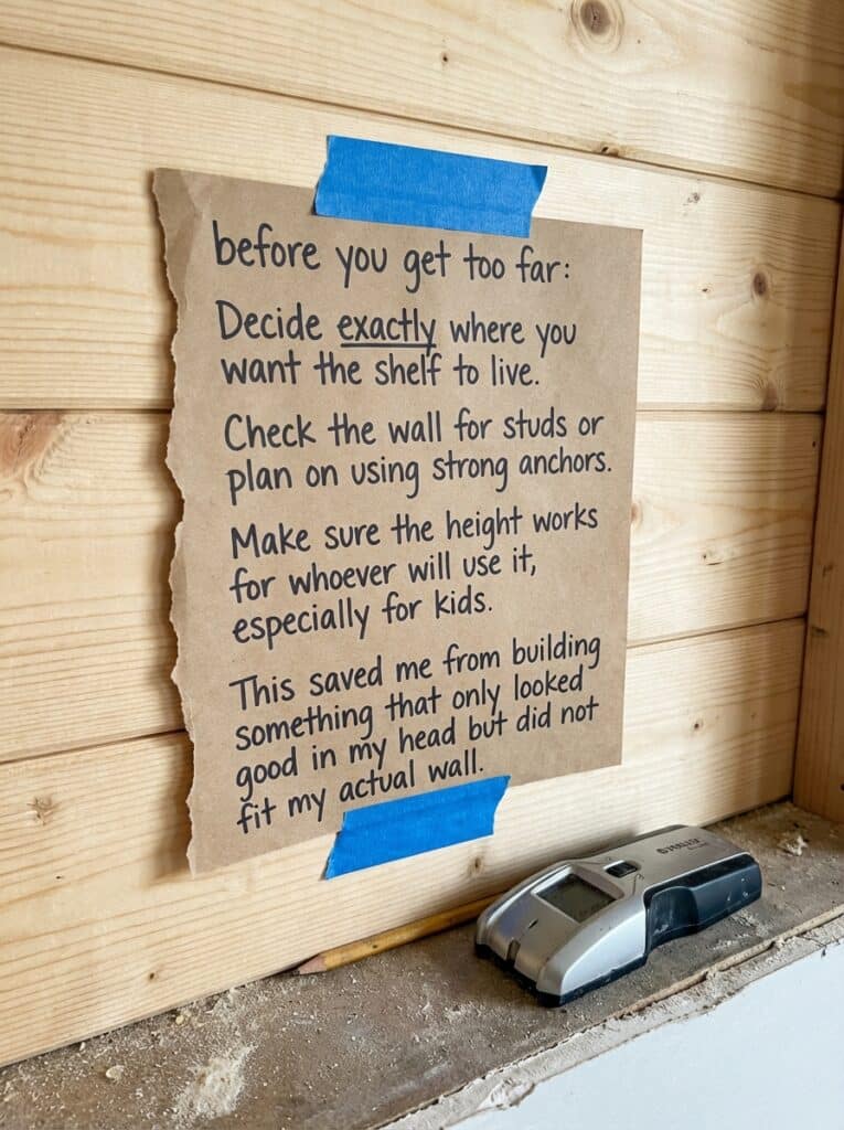ai-photo-studio-1766516448846-2 DIY shelving guide on cardboard taped to wood wall, highlighting planning, wall checking, and height considerations for shelf installation. | Sky Rye Design DIY shelving guide on cardboard taped to wood wall, highlighting planning, wall checking, and height considerations for shelf installation.