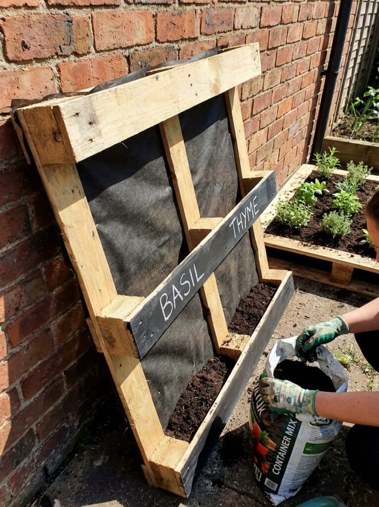 ai-photo-studio-1766677296422-2 DIY vertical garden with basil and thyme planter, using wooden pallets and container mix, against a brick wall. Ideal for small spaces. | Sky Rye Design DIY vertical garden with basil and thyme planter, using wooden pallets and container mix, against a brick wall. Ideal for small spaces.