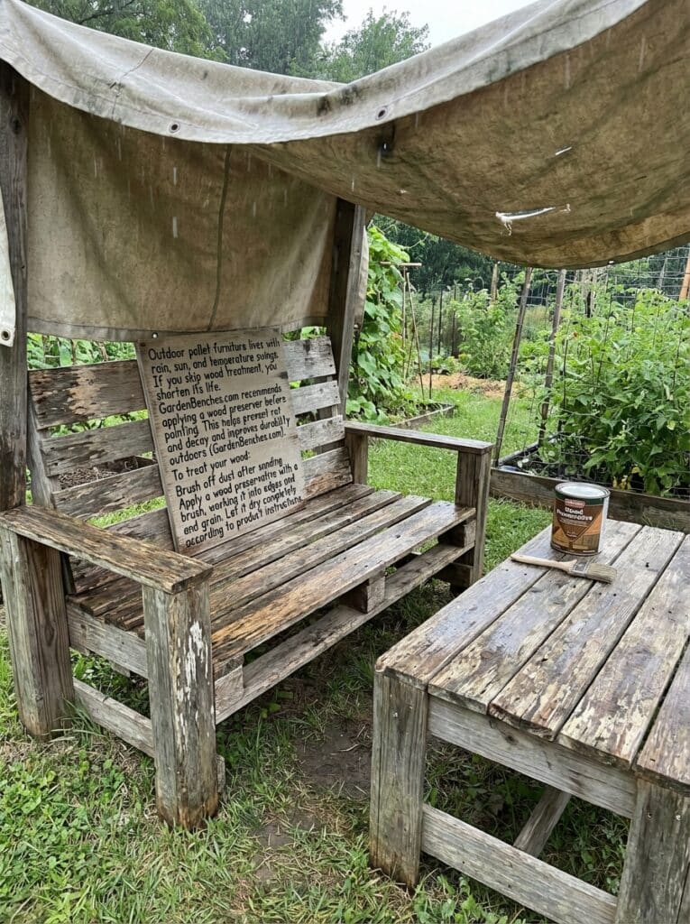ai-photo-studio-1766940672445-1 Wooden pallet bench and table in a garden under tarp, showcasing wood preservation tips for outdoor furniture durability. | Sky Rye Design Wooden pallet bench and table in a garden under tarp, showcasing wood preservation tips for outdoor furniture durability.