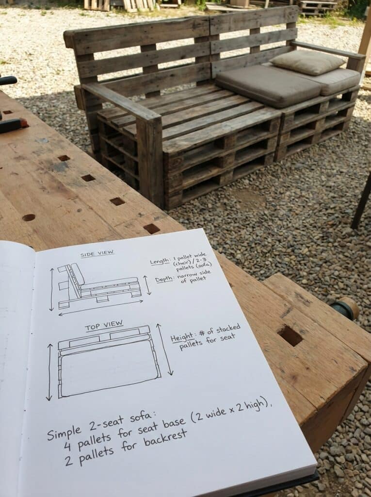 ai-photo-studio-1766940894040-2 DIY pallet sofa sketch with side and top views on a notebook, beside a wooden pallet couch outdoors, ideal for sustainable projects. | Sky Rye Design DIY pallet sofa sketch with side and top views on a notebook, beside a wooden pallet couch outdoors, ideal for sustainable projects.
