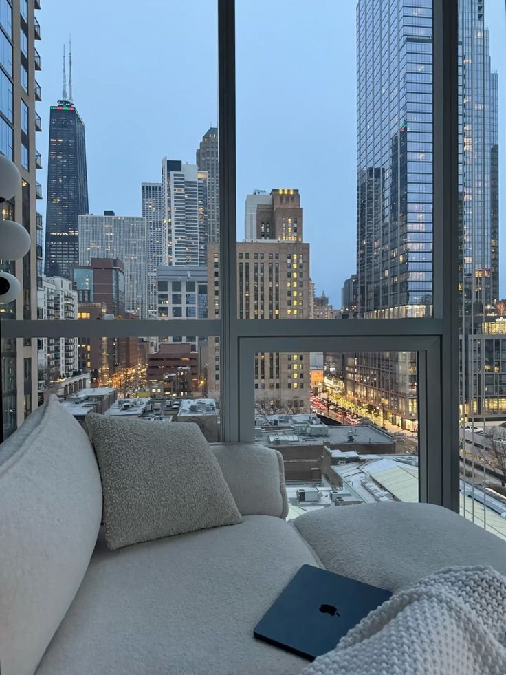 b4bf0f4e-7362-469e-82f4-56a3451eddd8 Modern cityscape from a cozy apartment with a plush sofa and tablet, featuring skyscrapers under a clear evening sky. | Sky Rye Design Modern cityscape from a cozy apartment with a plush sofa and tablet, featuring skyscrapers under a clear evening sky.