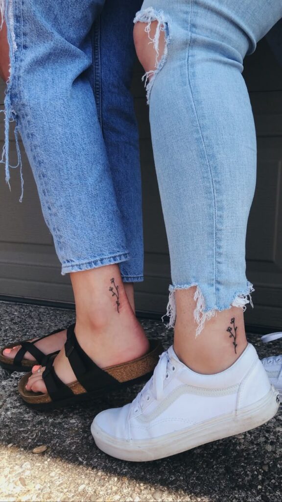 besties forever Matching ankle tattoos with a delicate floral design on individuals wearing distressed jeans and casual footwear. | Sky Rye Design Matching ankle tattoos with a delicate floral design on individuals wearing distressed jeans and casual footwear.
