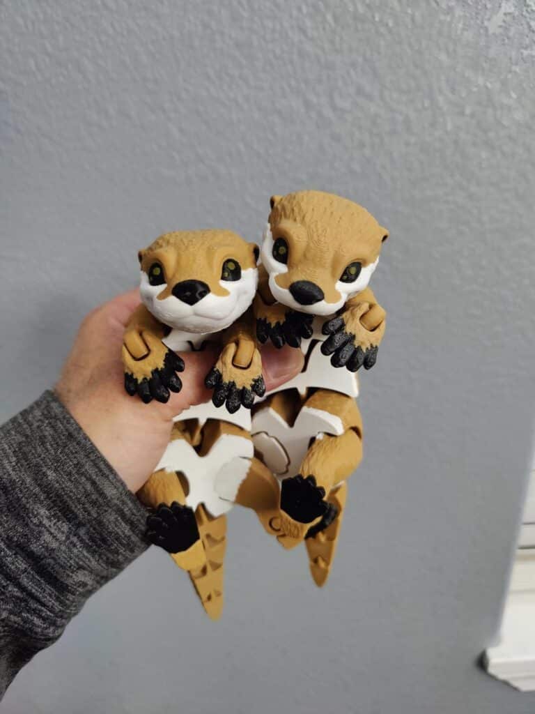 bfea20b2df0c704ef0f6d7ff79de0dbe Two cute otter figurines held in hand against a gray wall. Perfect toys for children or otter enthusiasts. | Sky Rye Design Two cute otter figurines held in hand against a gray wall. Perfect toys for children or otter enthusiasts. 5 STL website keywords.