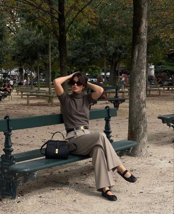 brown outfit _ beige _ ootd _ fall season _ ballerine _ ballerina _ miumiu _ celine _ fall outfit Fashionable woman in sunglasses sitting on a park bench, wearing neutral tones, with bag beside her, surrounded by trees and people strolling. | Sky Rye Design Fashionable woman in sunglasses sitting on a park bench, wearing neutral tones, with bag beside her, surrounded by trees and people strolling.