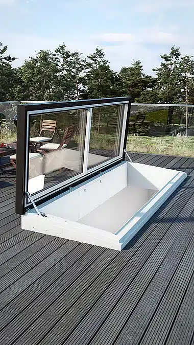 Rooftop terrace with modern glass hatch, providing access to an underground space. Trees and furniture are visible in the background.