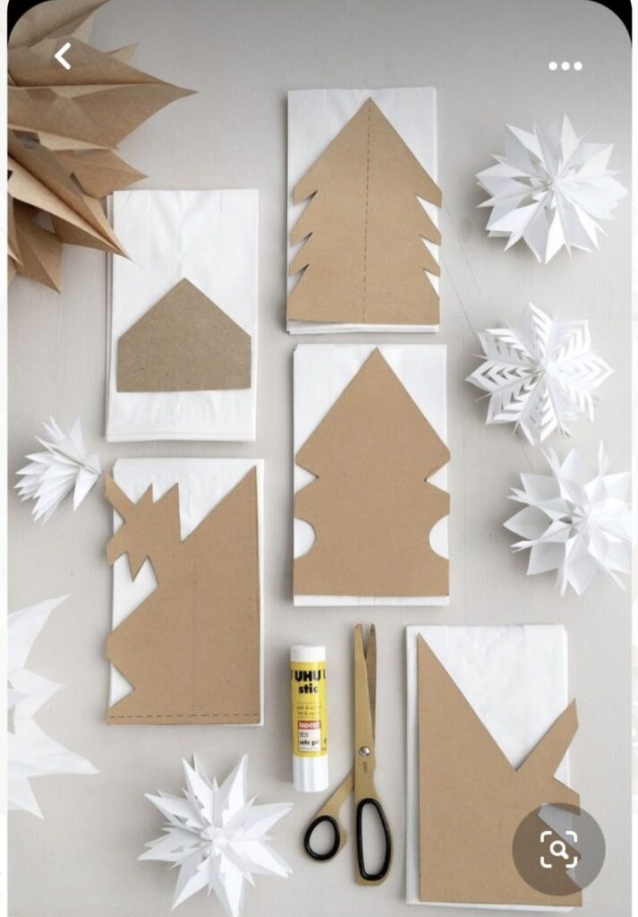 Screenshot DIY Christmas crafts with paper snowflakes and cardboard cutouts on a table, featuring scissors and glue for festive decoration making. | Sky Rye Design DIY Christmas crafts with paper snowflakes and cardboard cutouts on a table, featuring scissors and glue for festive decoration making.