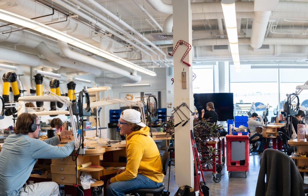 e263fb0f4db350a4ae5f2d3cd282ee2b Modern workshop with people collaborating at workbenches, surrounded by tools and equipment, in a bright industrial space. | Sky Rye Design Modern workshop with people collaborating at workbenches, surrounded by tools and equipment, in a bright industrial space.