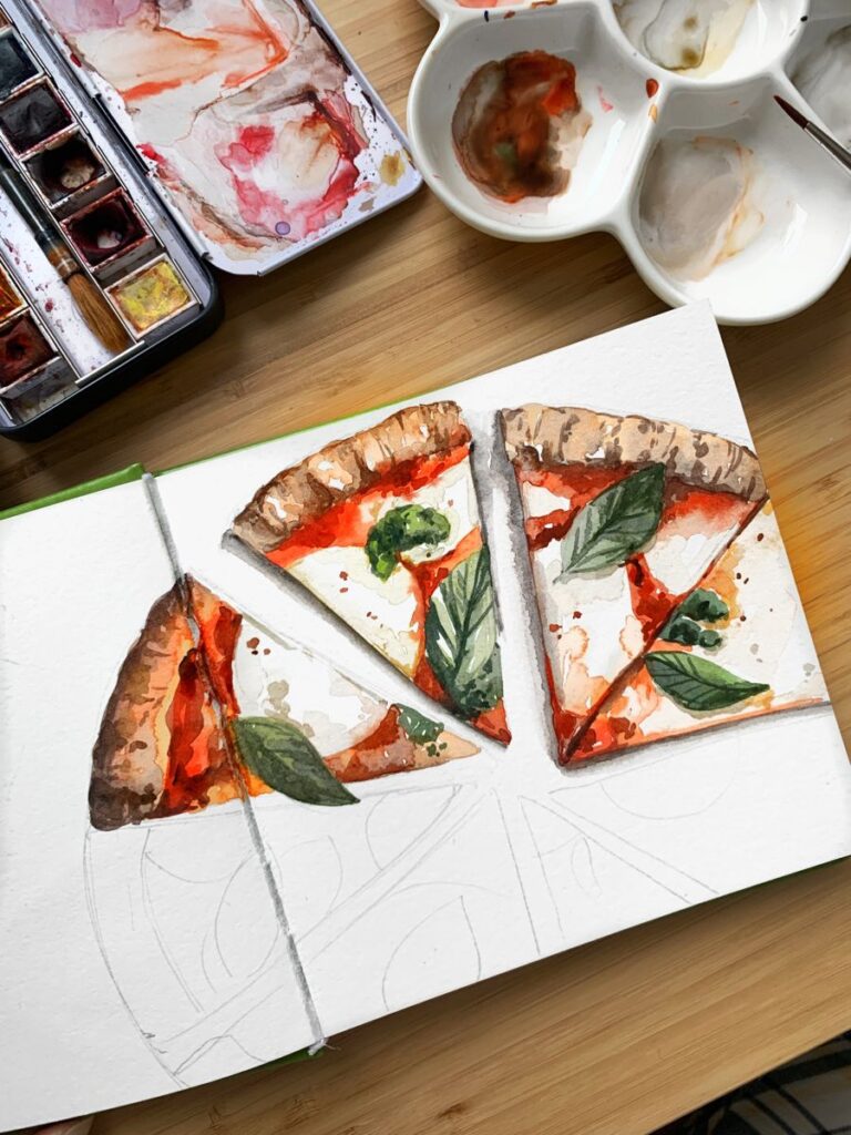 Watercolor painting of pizza slices with basil, accompanied by a paint palette and watercolors, on a wooden table.