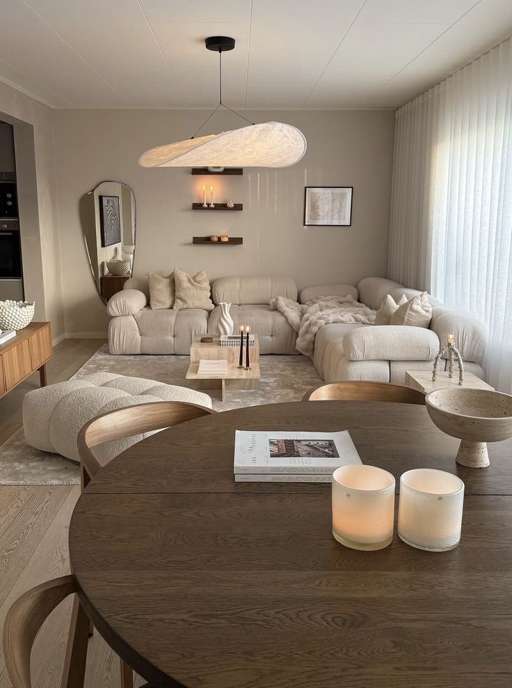 f335f7fc-89b4-48ee-a75a-99fc12fc95d6 Modern living room with beige sofa, wooden table with books and candles, and minimalist decor. Soft lighting creates a cozy atmosphere. | Sky Rye Design Modern living room with beige sofa, wooden table with books and candles, and minimalist decor. Soft lighting creates a cozy atmosphere.