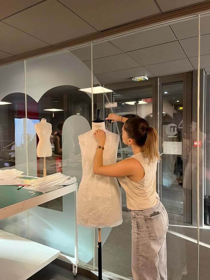 fashion class Fashion student adjusting a dress on a mannequin in a design studio. | Sky Rye Design Fashion student adjusting a dress on a mannequin in a design studio.