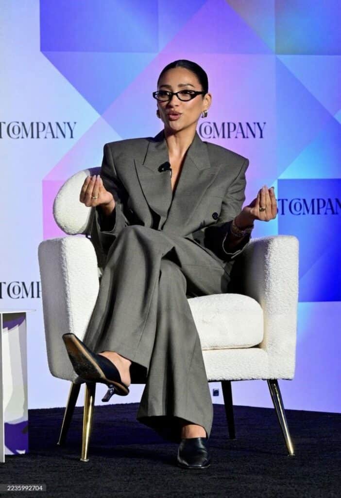 Person in a gray suit speaks on stage at a conference.
