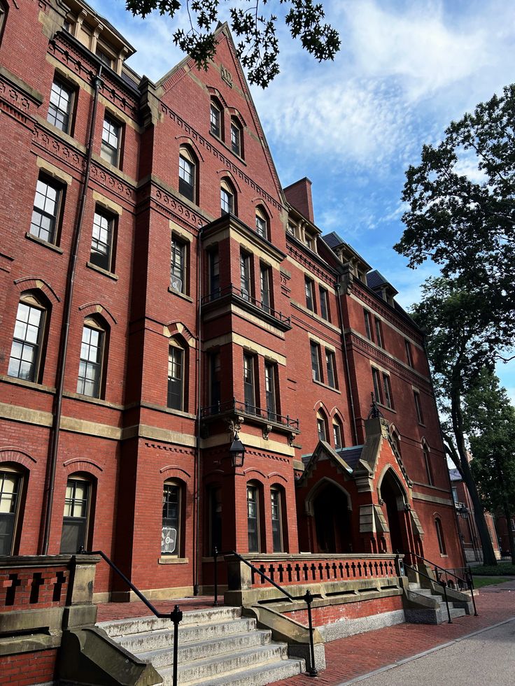 harvard dorm Red brick university building with Victorian architecture, showcasing arched windows, decorative details, and clear blue sky in the background. | Sky Rye Design Red brick university building with Victorian architecture, showcasing arched windows, decorative details, and clear blue sky in the background.