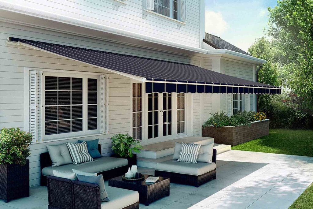 homeguide-SunSetter-Series-motorized-awning Modern patio with comfortable seating under a retractable awning, offering shade and style for outdoor relaxation. | Sky Rye Design Modern patio with comfortable seating under a retractable awning, offering shade and style for outdoor relaxation.