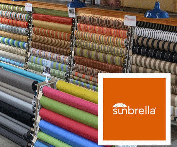 image Colorful rolls of Sunbrella fabric displayed in a store, showcasing various patterns and designs for interior and exterior use. | Sky Rye Design Colorful rolls of Sunbrella fabric displayed in a store, showcasing various patterns and designs for interior and exterior use.