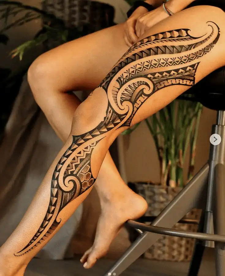 Intricate tribal leg tattoo design on a seated person, showcasing bold patterns and rich cultural artistry.