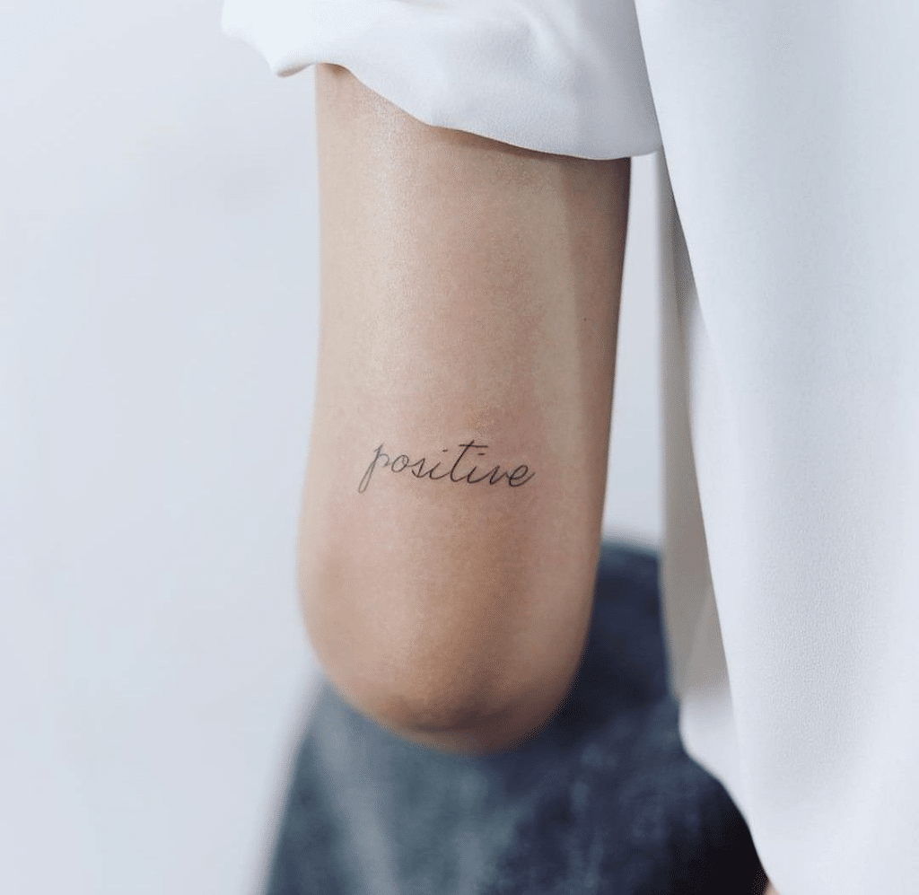 image52-1 Minimalist tattoo of the word positive on an arm, conveying optimism and positivity in elegant cursive script. | Sky Rye Design Minimalist tattoo of the word positive on an arm, conveying optimism and positivity in elegant cursive script.
