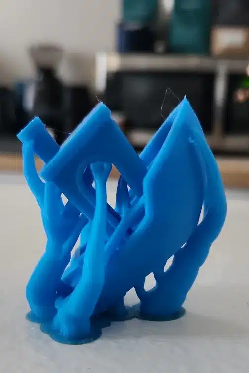 img_1_88a23fe5-5b40-4f51-9443-89ab2bad768d Unfinished blue 3D print of hands holding a square, with stringing issues, on a blurred background. | Sky Rye Design Unfinished blue 3D print of hands holding a square, with stringing issues, on a blurred background.