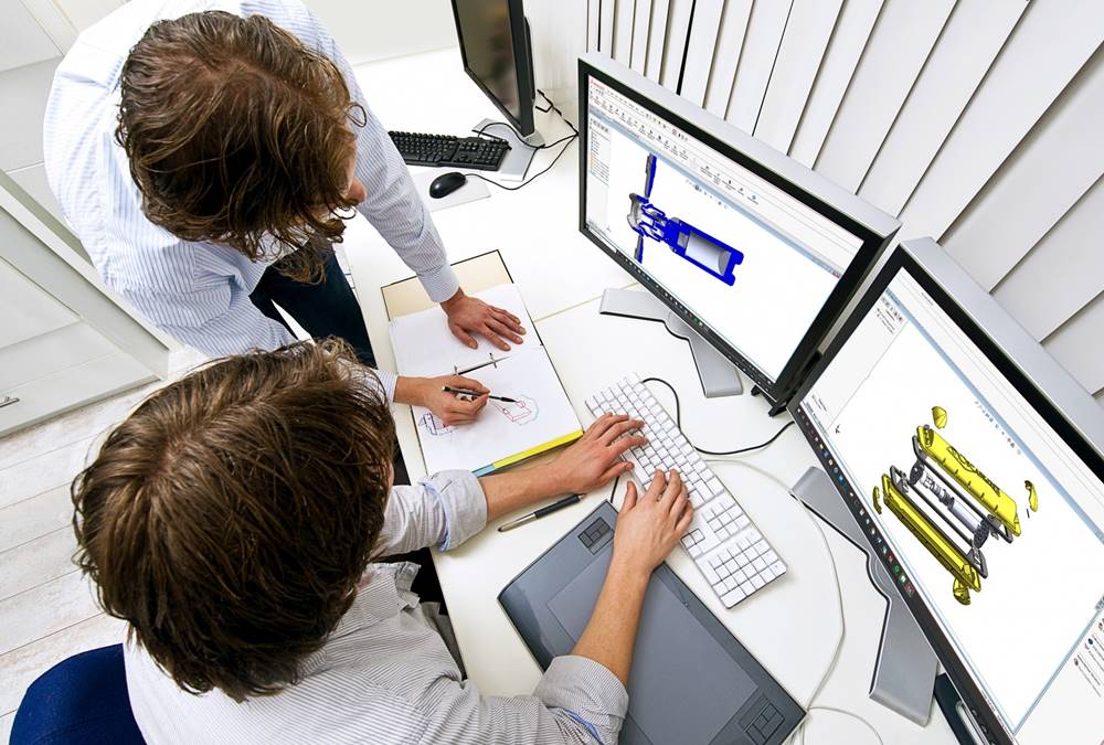 industrial-design-cad-design-for-manufacture Two professionals collaborating on 3D design at a workstation with dual monitors and a drawing pad, focused on engineering solutions. | Sky Rye Design Two professionals collaborating on 3D design at a workstation with dual monitors and a drawing pad, focused on engineering solutions.