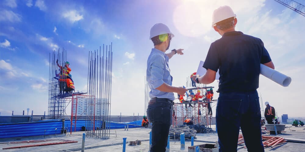 new-construction-services-1000x500pxl Construction site with engineers in hard hats reviewing plans, scaffolding in the background against a sunny sky. | Sky Rye Design Construction site with engineers in hard hats reviewing plans, scaffolding in the background against a sunny sky. Construction Engineering Services in Apex