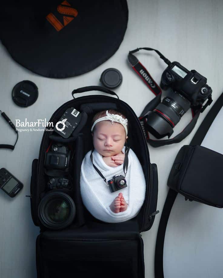 newborn photography Newborn baby wrapped in a camera backpack, surrounded by camera gear, wearing a miniature camera. Creative photography concept. | Sky Rye Design Newborn baby wrapped in a camera backpack, surrounded by camera gear, wearing a miniature camera. Creative photography concept.