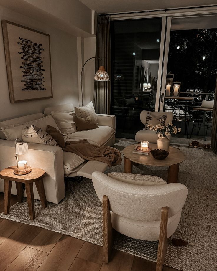 pov_ the warmth and simplicity of a home with Cozy living room with neutral decor, soft lighting, beige couch, armchairs, wooden tables, and candles creating a warm, inviting ambiance. | Sky Rye Design Cozy living room with neutral decor, soft lighting, beige couch, armchairs, wooden tables, and candles creating a warm, inviting ambiance.