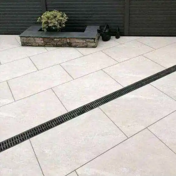 preventing-water-pooling-on-porcelain-patio-surfaces Modern patio design with large stone tiles and a linear drainage grate, featuring a planter with greenery in a contemporary outdoor setting. | Sky Rye Design Modern patio design with large stone tiles and a linear drainage grate, featuring a planter with greenery in a contemporary outdoor setting.