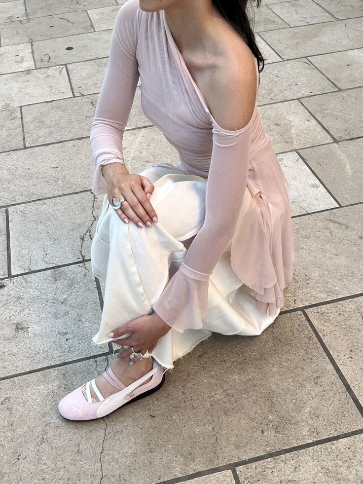 puma ballet Woman in stylish off-shoulder pink top and white pants kneels on tiled floor, showcasing pink ballet flats and elegant jewelry. | Sky Rye Design Woman in stylish off-shoulder pink top and white pants kneels on tiled floor, showcasing pink ballet flats and elegant jewelry.
