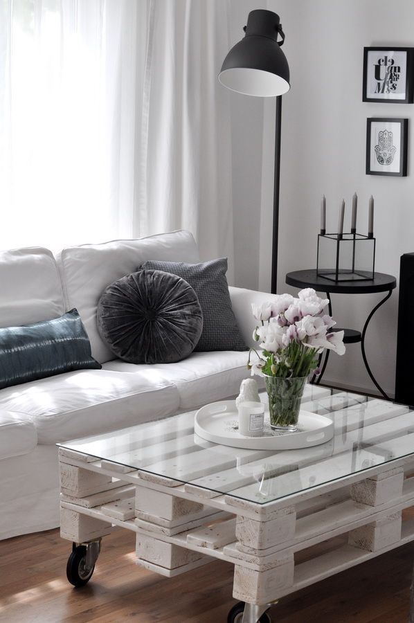 summer Modern living room with a white sofa, a rustic pallet coffee table, glass vase with tulips, and a floor lamp, creating a cozy atmosphere. | Sky Rye Design Modern living room with a white sofa, a rustic pallet coffee table, glass vase with tulips, and a floor lamp, creating a cozy atmosphere.