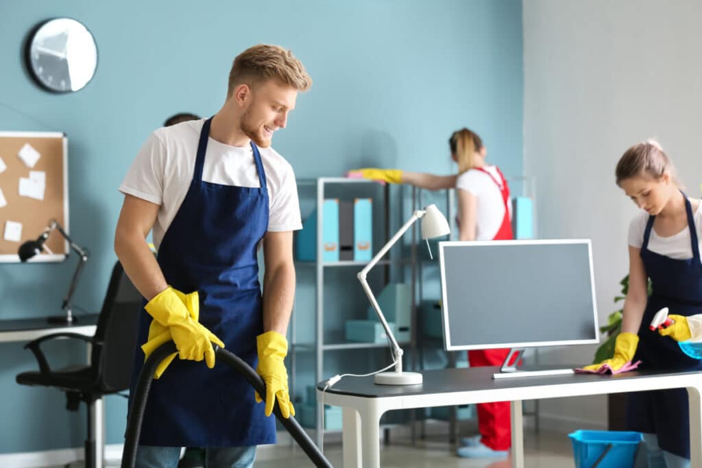 Cleaning crew dusting and vacuuming a modern office, maintaining workspace hygiene.
